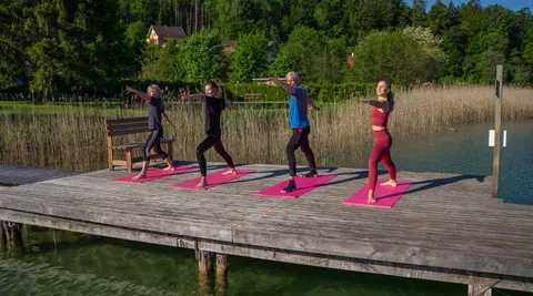 Mehrere Personen machen Yoga am Steg des Woerthersees