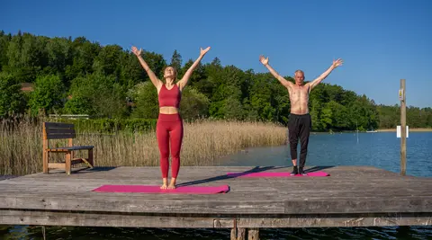 Zwei Personen machen Yoga am Steg des Woerthersees